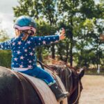 Kind sitzt auf einem Pferd und macht therapeutisches Reiten