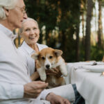 Älteres Paar sitzt am Tisch mit einem Hund